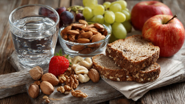 Healthy study snacks including water, nuts, fruits, and whole grains on a desk